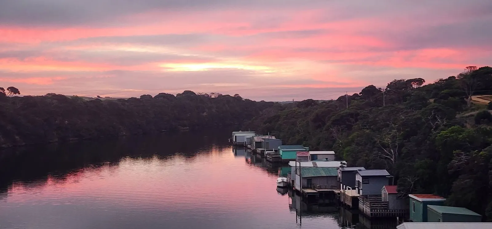 A pink sunset over the row of boat sheds along the Glenelg River