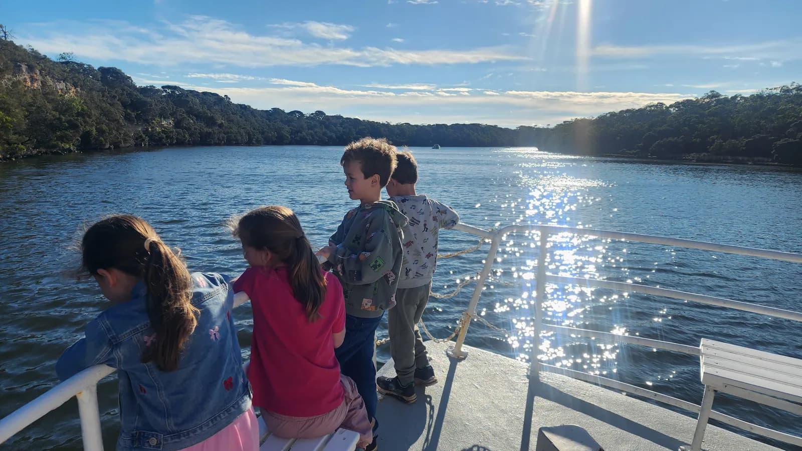 Children lined along the rail as sunlight scatters across the Glenelg River