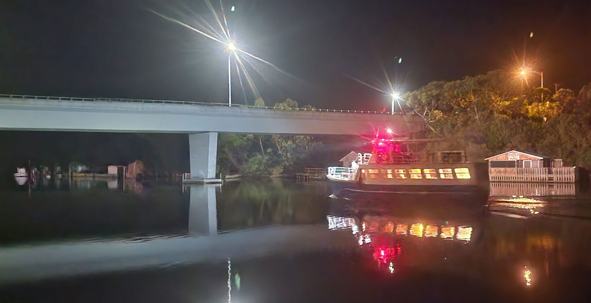 MV Mini Munya lit up at night beside the Nelson bridge, set for a dinner cruise
